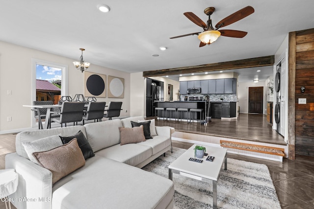 living room featuring stacked washer / dryer, a chandelier, a ceiling fan, recessed lighting, and baseboards