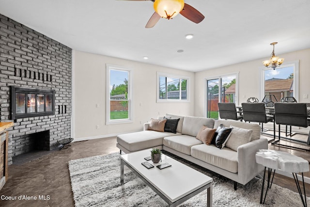 living area featuring a fireplace, plenty of natural light, a chandelier, and a ceiling fan