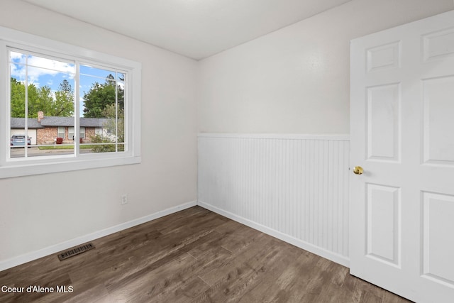 empty room with wood finished floors, wainscoting, and baseboards