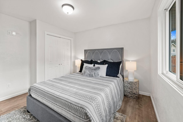 bedroom with baseboards, wood finished floors, and a closet