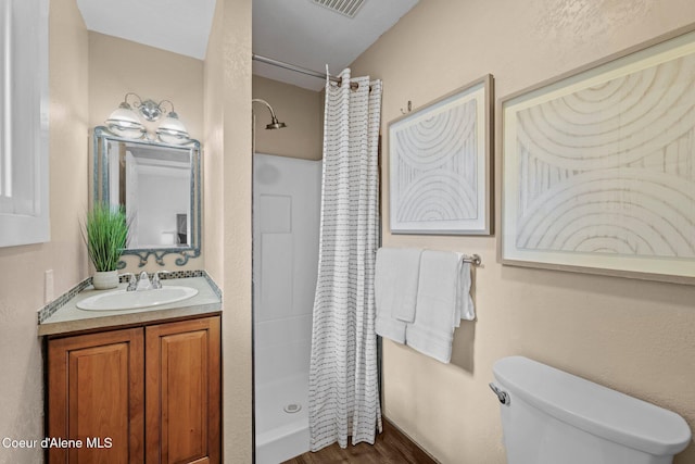 full bath featuring a shower stall, toilet, vanity, and wood finished floors