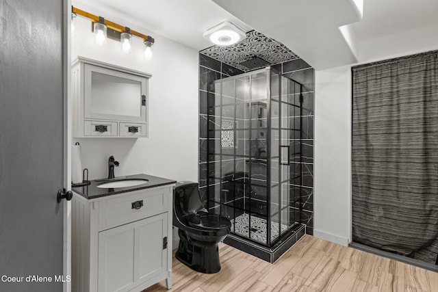 full bathroom featuring a stall shower, toilet, vanity, and wood finished floors