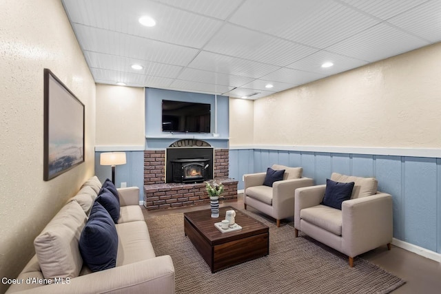 living room featuring a wainscoted wall, a textured wall, recessed lighting, and a brick fireplace