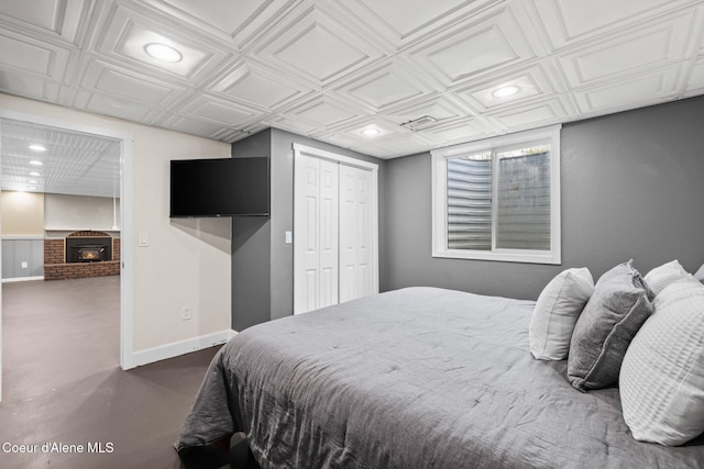 bedroom featuring recessed lighting, baseboards, a closet, an ornate ceiling, and a brick fireplace