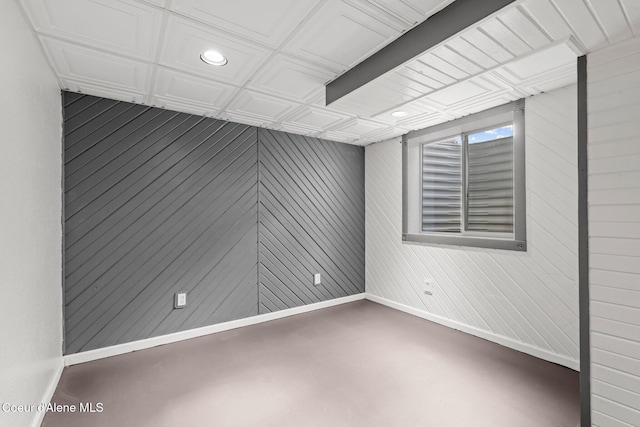 spare room with baseboards, wood walls, recessed lighting, and concrete floors