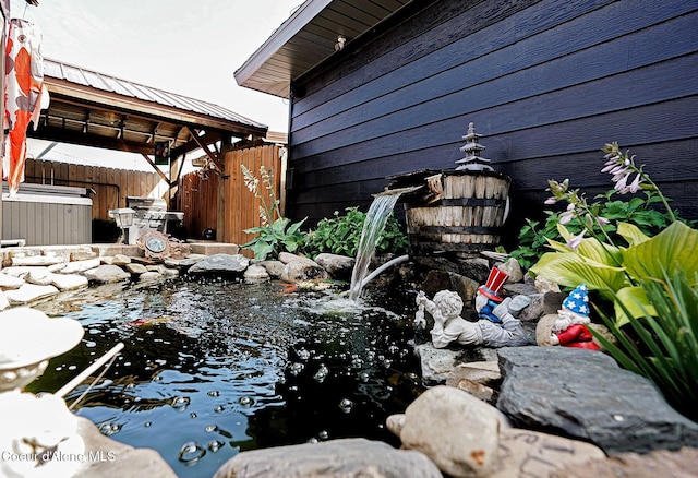 exterior view of a jacuzzi, fence, and a garden pond
