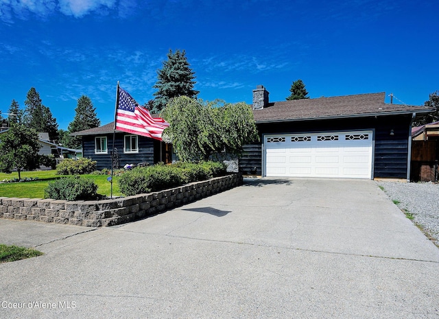view of front of home featuring driveway, a chimney, and an attached garage