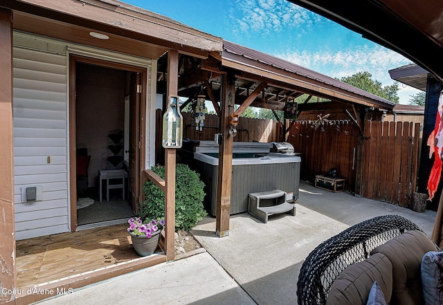 view of patio featuring a hot tub, fence, a gazebo, and a deck