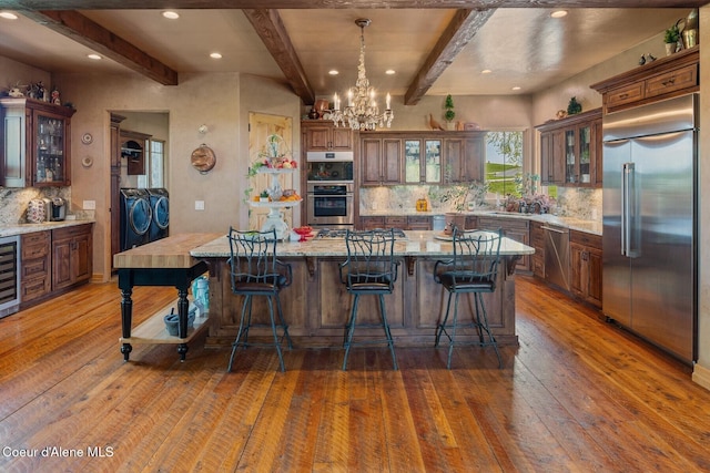16829 S Lazurite Dr, Coeur Dalene, ID 83814 - kitchen featuring stainless steel appliances, washing machine and clothes dryer, hardwood / wood-style flooring, beamed ceiling, and a chandelier