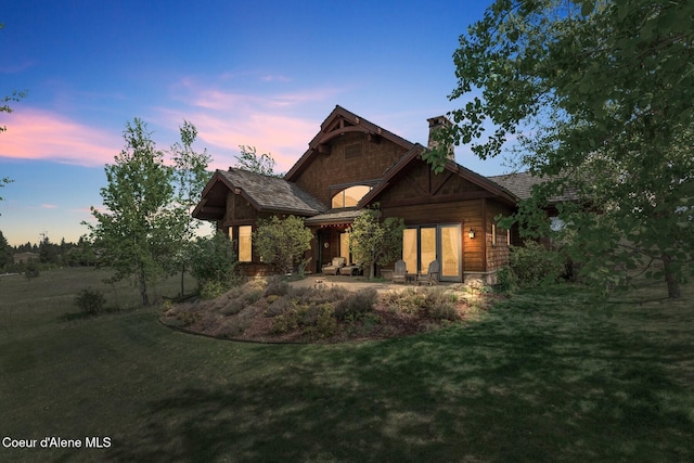 16829 S Lazurite Dr, Coeur Dalene, ID 83814 - back of property at dusk featuring a chimney and a yard