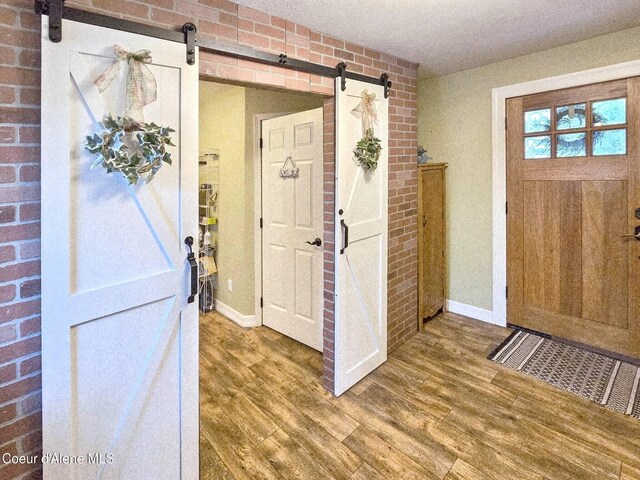 29429 N Silver Meadows Loop, Athol, ID 83801 - foyer featuring a barn door, wood finished floors, baseboards, and brick wall