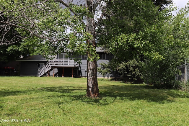 view of green lawn with stairway and a wooden deck