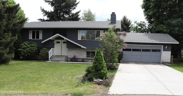 split foyer home featuring brick siding, driveway, a chimney, an attached garage, and a front yard