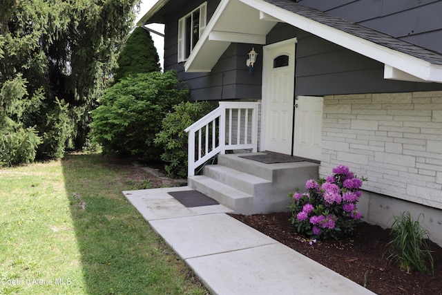 doorway to property with a lawn and roof with shingles