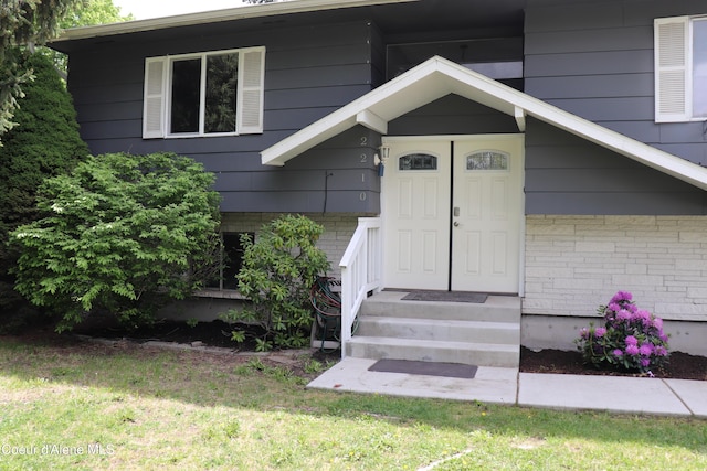 property entrance with brick siding and a lawn