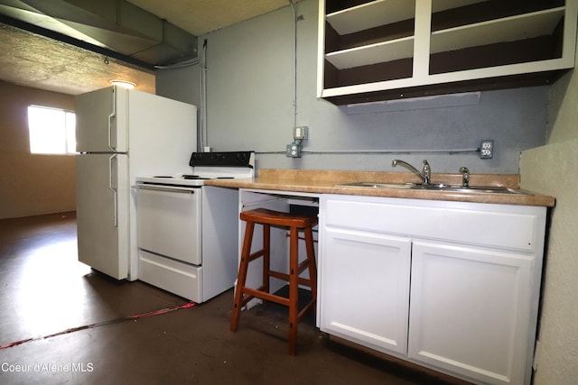 kitchen with white appliances, concrete floors, a sink, and white cabinetry