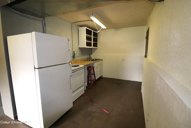 kitchen with white appliances, concrete floors, a sink, and white cabinetry