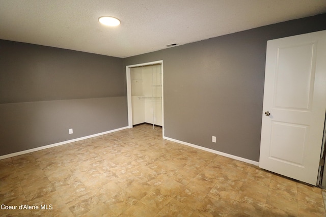 unfurnished bedroom featuring a closet, baseboards, and a textured ceiling