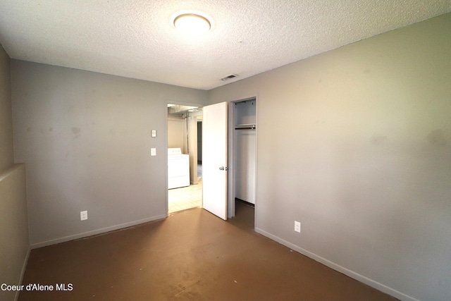 unfurnished bedroom featuring washer / dryer, a closet, baseboards, a textured ceiling, and concrete flooring