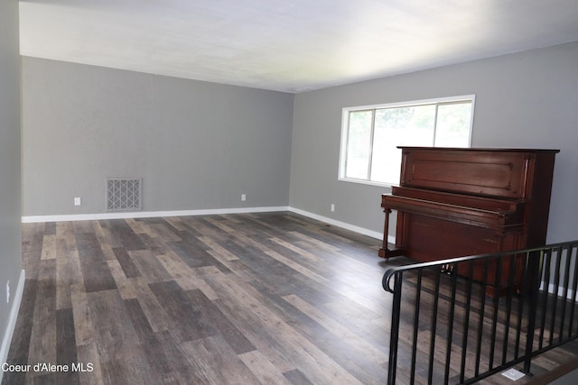 unfurnished room with dark wood-style flooring and baseboards
