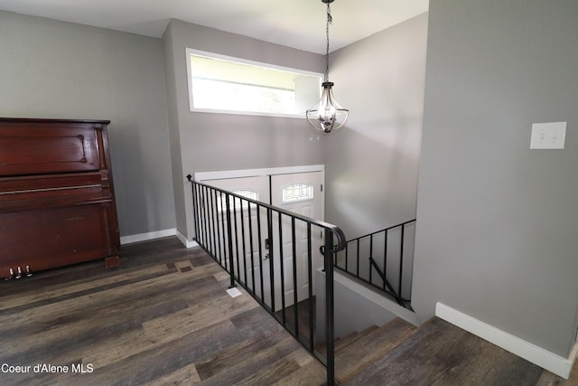staircase featuring wood finished floors, a chandelier, and baseboards