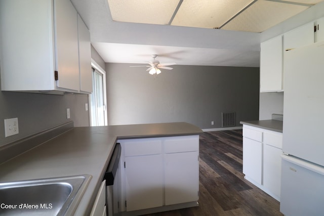 kitchen featuring freestanding refrigerator, a peninsula, ceiling fan, dark wood-type flooring, and white cabinetry