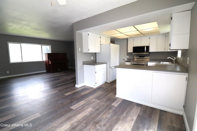 kitchen featuring appliances with stainless steel finishes, a sink, dark wood-style floors, and white cabinetry