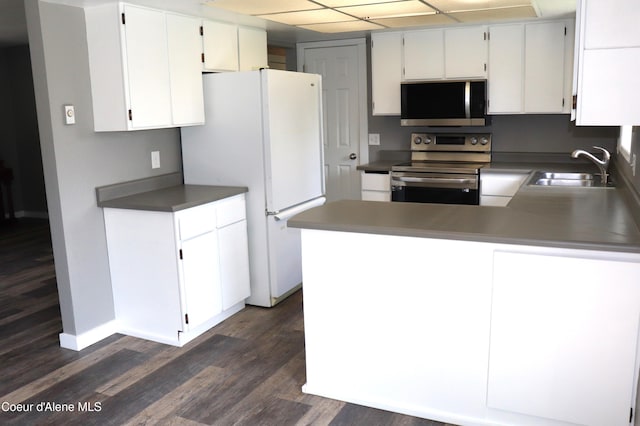 kitchen featuring stainless steel appliances, a sink, dark wood-style flooring, white cabinets, and baseboards
