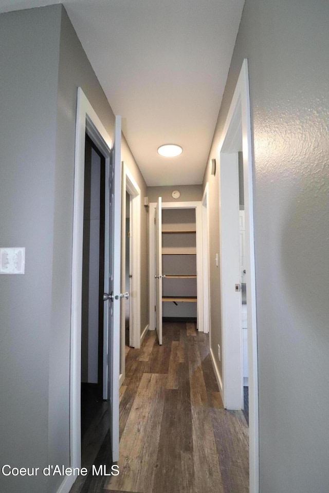 corridor featuring dark wood-style floors and baseboards