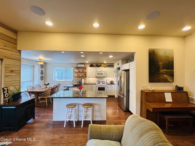 8351 N Audubon Dr, Hayden, ID 83835 - kitchen featuring white appliances, white cabinets, dark wood-type flooring, a kitchen breakfast bar, and recessed lighting
