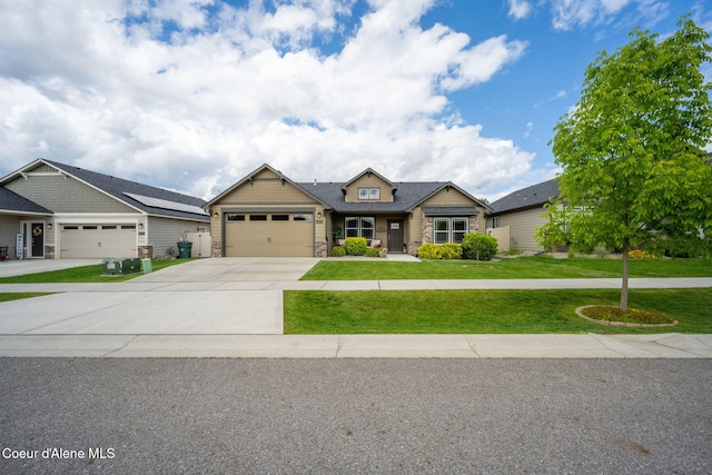 craftsman-style home featuring stone siding, driveway, an attached garage, and a front yard