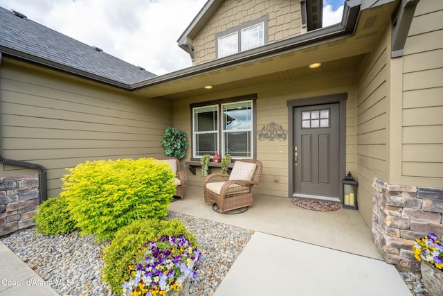 entrance to property featuring a shingled roof and covered porch