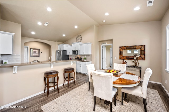 dining area with dark wood-style flooring, recessed lighting, vaulted ceiling, arched walkways, and baseboards