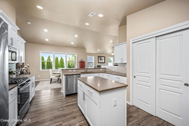 kitchen featuring stainless steel appliances, a sink, a peninsula, tasteful backsplash, and recessed lighting