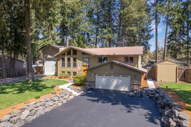 view of front of house with asphalt driveway, a storage shed, metal roof, and an outdoor structure