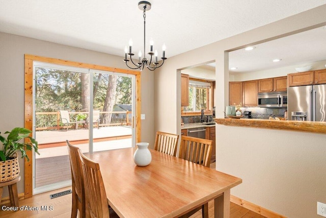 dining room with a chandelier, recessed lighting, light wood-style flooring, and baseboards
