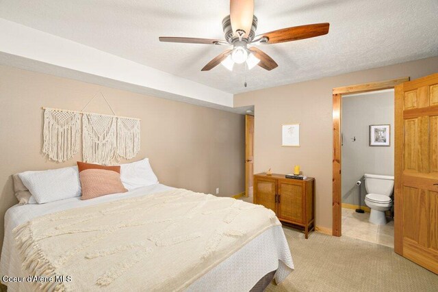 bedroom featuring connected bathroom, light carpet, a ceiling fan, and baseboards