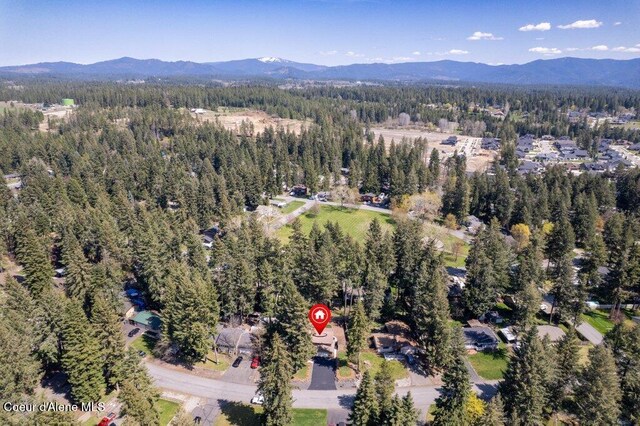aerial view of property and surrounding area featuring a heavily wooded area and a mountainous background