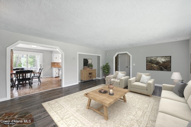 6699 Colburn Culver Rd, Sandpoint, ID 83864 - living room featuring arched walkways, a textured ceiling, wood finished floors, and baseboards