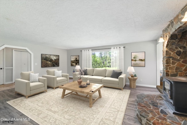 6699 Colburn Culver Rd, Sandpoint, ID 83864 - living area with a textured ceiling, a wood stove, wood finished floors, baseboards, and arched walkways