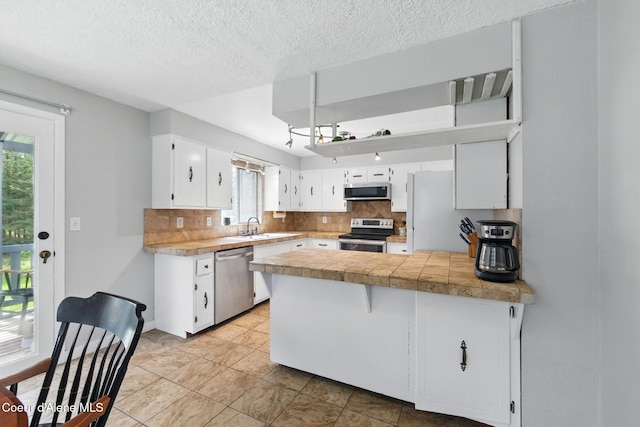 6699 Colburn Culver Rd, Sandpoint, ID 83864 - kitchen featuring appliances with stainless steel finishes, a peninsula, a sink, backsplash, and white cabinetry