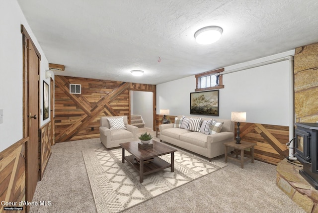 6699 Colburn Culver Rd, Sandpoint, ID 83864 - carpeted living room featuring wood walls, a wood stove, and a textured ceiling
