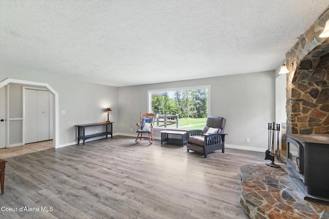 6699 Colburn Culver Rd, Sandpoint, ID 83864 - living area with a textured ceiling, wood finished floors, a wood stove, arched walkways, and baseboards