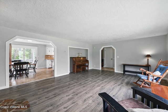 6699 Colburn Culver Rd, Sandpoint, ID 83864 - living area featuring arched walkways, a textured ceiling, wood finished floors, and baseboards