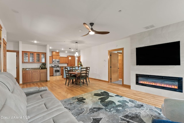 4461 W Greenchain Loop # 5, Coeur Dalene, ID 83814 - living room featuring light wood-type flooring, a ceiling fan, a tile fireplace, baseboards, and recessed lighting