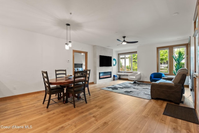 4461 W Greenchain Loop # 5, Coeur Dalene, ID 83814 - dining area featuring light wood finished floors, a fireplace, a ceiling fan, and baseboards