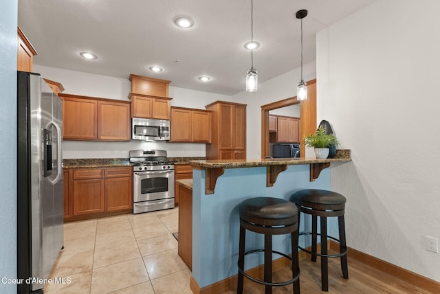 4461 W Greenchain Loop # 5, Coeur Dalene, ID 83814 - kitchen with appliances with stainless steel finishes, brown cabinets, dark stone countertops, a breakfast bar area, and recessed lighting