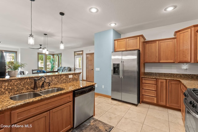 4461 W Greenchain Loop # 5, Coeur Dalene, ID 83814 - kitchen with appliances with stainless steel finishes, a sink, brown cabinets, dark stone countertops, and hanging light fixtures