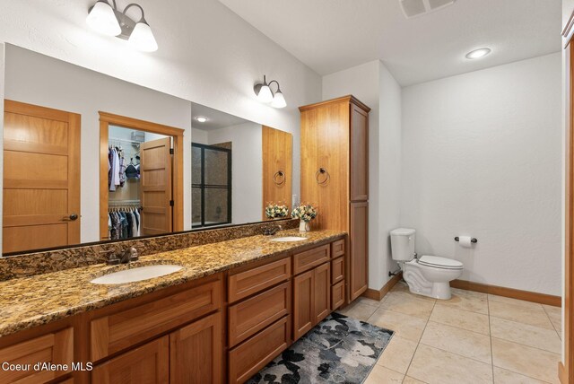 4461 W Greenchain Loop # 5, Coeur Dalene, ID 83814 - bathroom with a stall shower, baseboards, toilet, a walk in closet, and double vanity