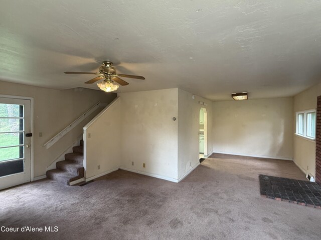 812 Silver St, Wallace, ID 83873 - unfurnished living room featuring a ceiling fan, carpet flooring, stairs, arched walkways, and baseboards